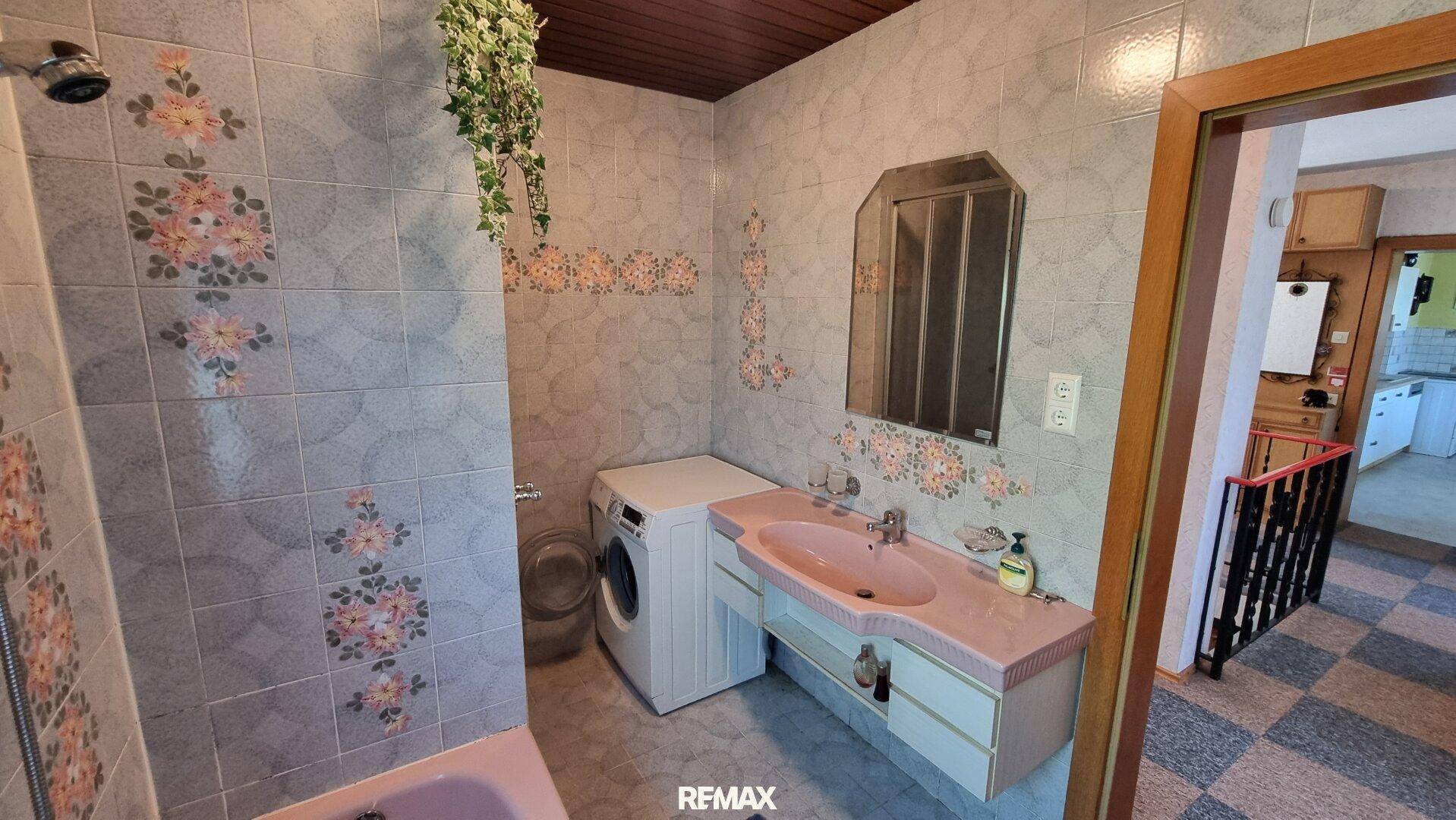 Badezimmer im Stil der 80er Jahre mit rosa Waschbecken, Dusche und Waschmaschine.