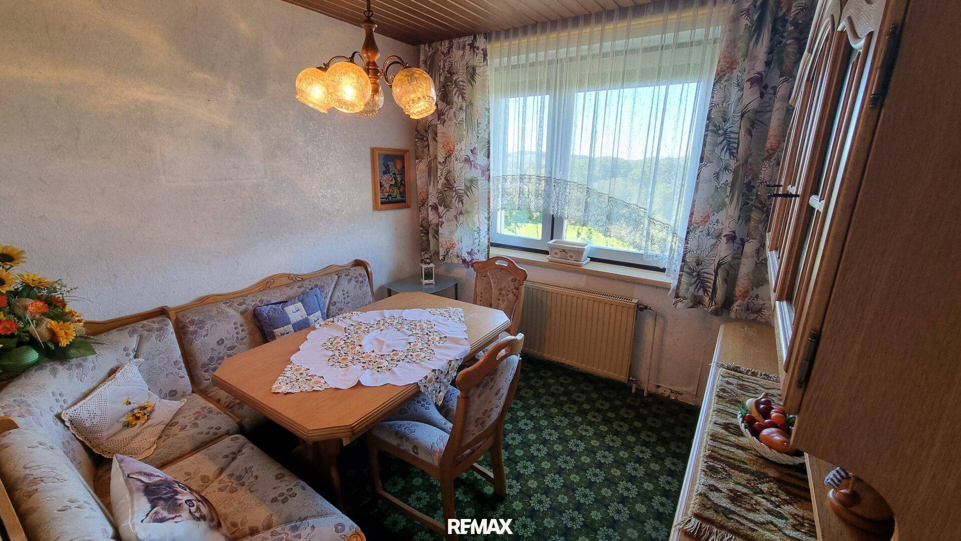 Gemütlicher Essbereich mit Eckbank, Holztisch und Blick ins Grüne durch das Fenster.