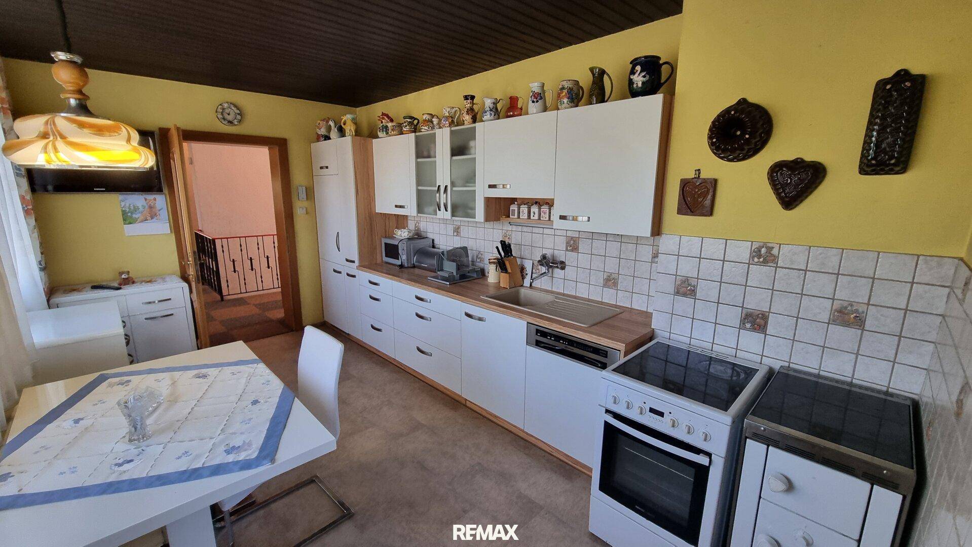 Traditionelle Küche mit weißen Schränken, Holztheke und einem kleinen Esstisch.