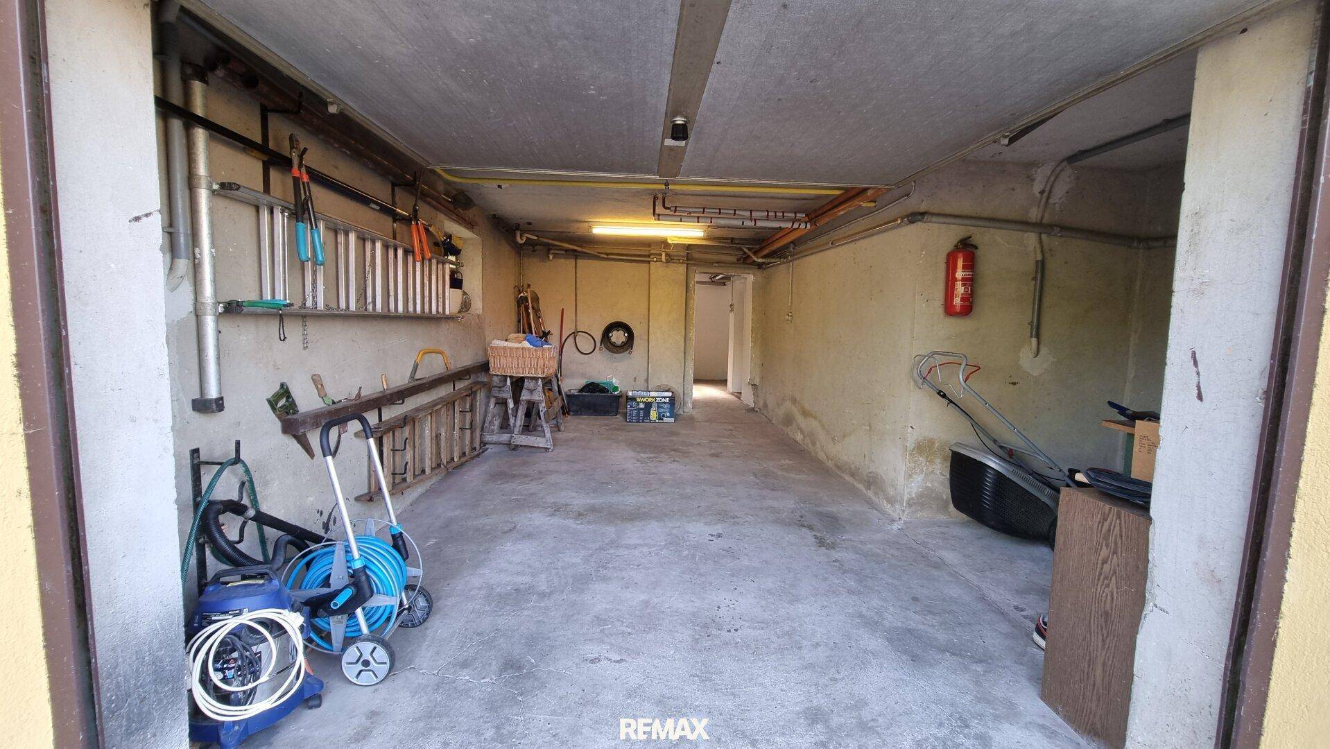 Geräumige Garage mit Betonboden, Stauraum und Zugang zu weiteren Räumen.