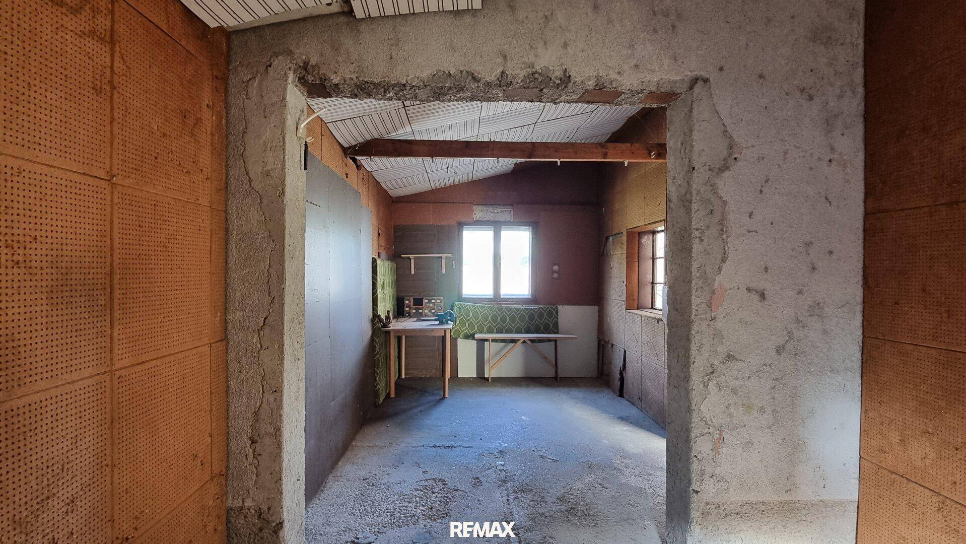 Unfertiger Raum mit sichtbarer Isolierung und einem Fenster, bereit für den Ausbau.