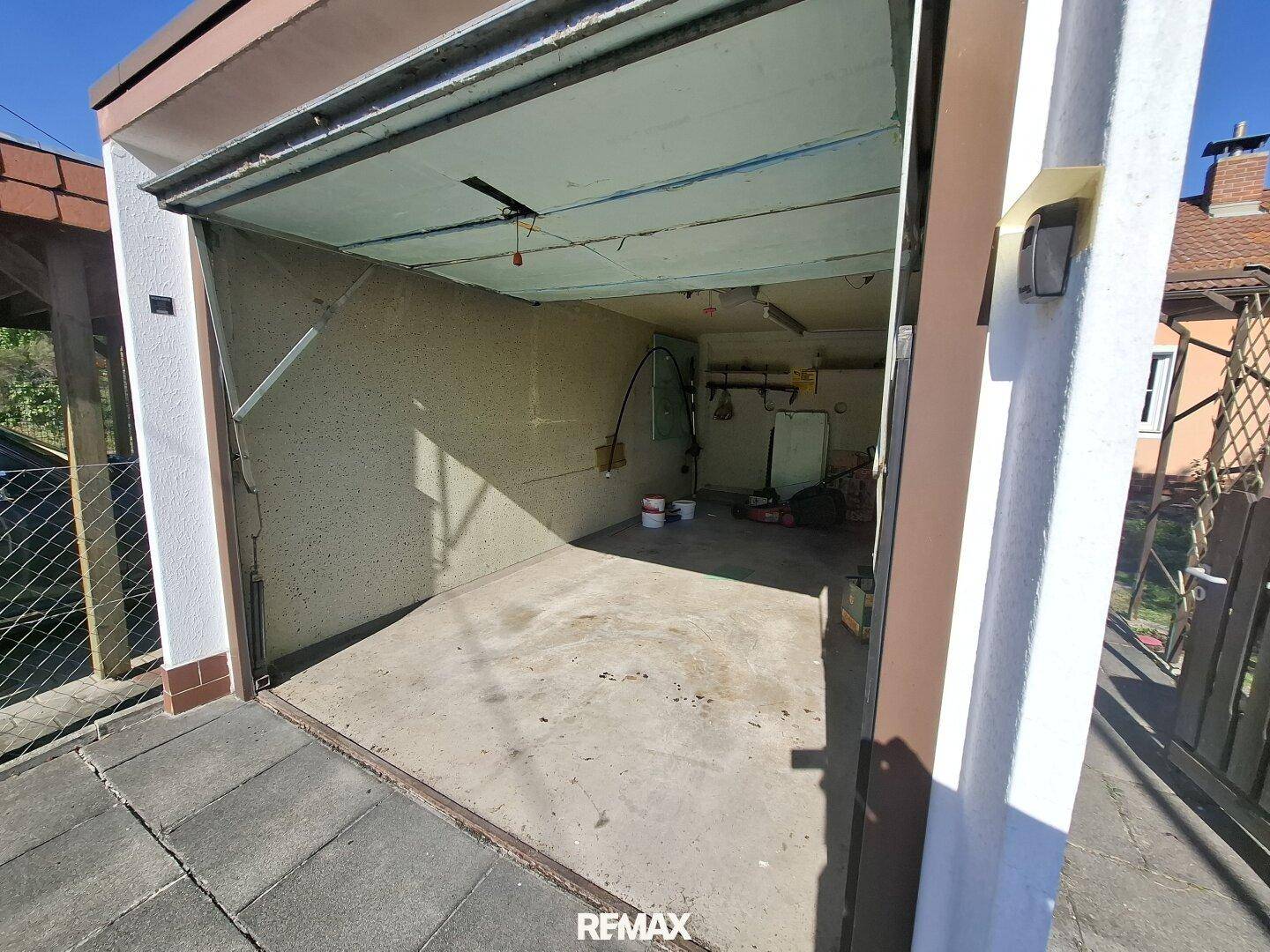 Einzelgarage mit offenem Tor und Betonboden, bietet Platz für ein Fahrzeug und Lagerung.
