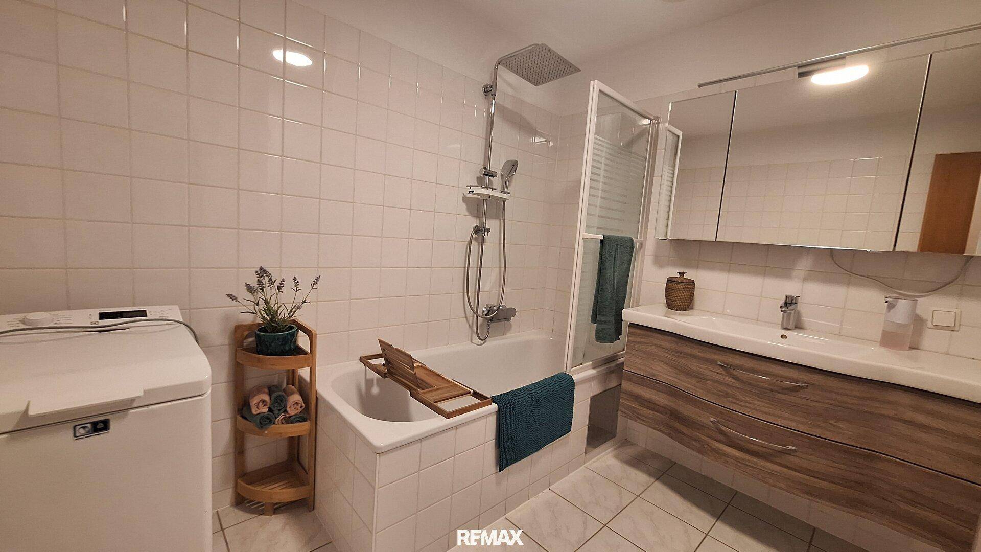 Modernes Badezimmer mit Badewanne, Duschfunktion und Waschmaschinenanschluss.