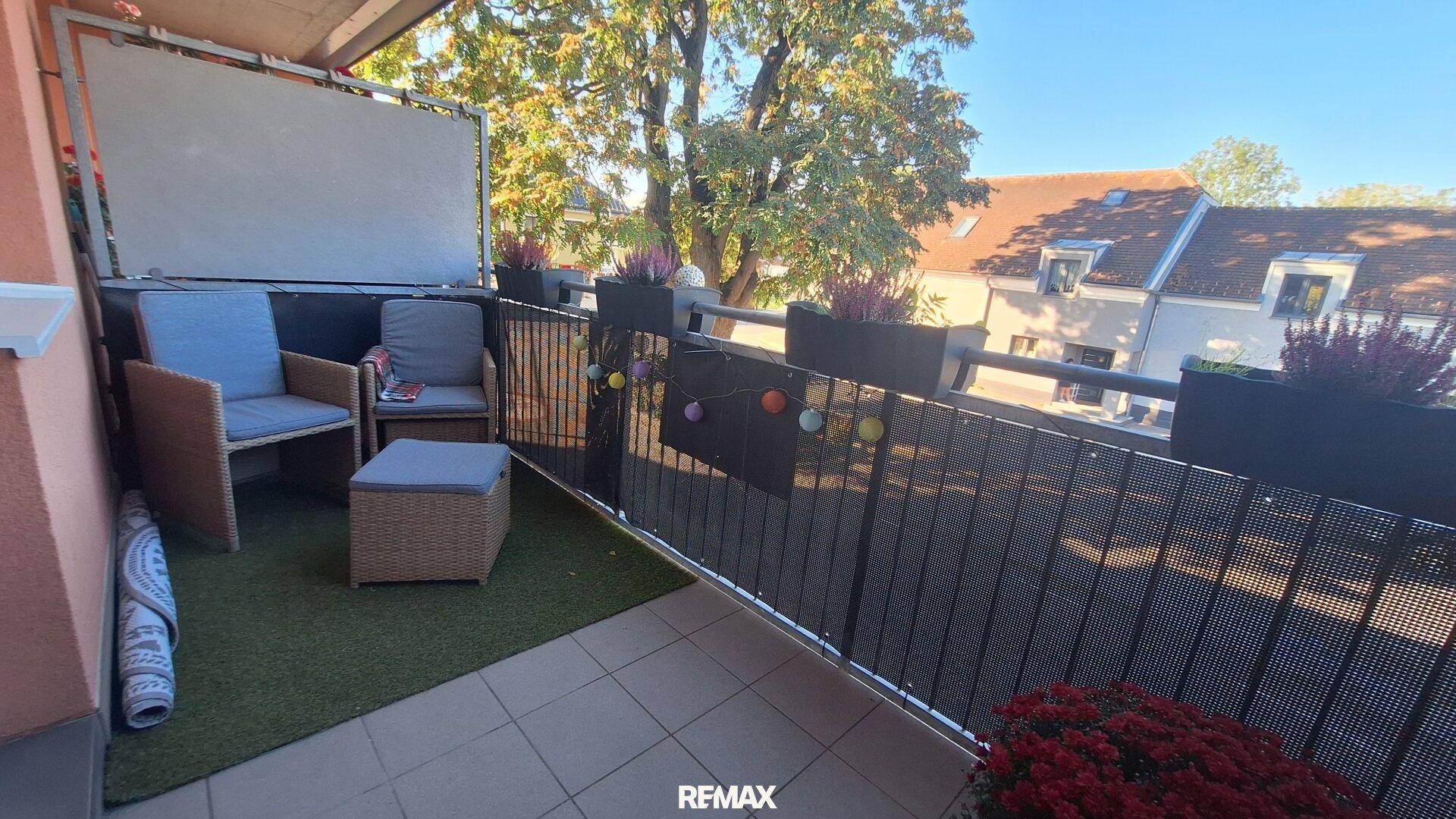Gemütlicher Balkon mit Sitzgelegenheiten, Kunstrasen und Pflanzen.