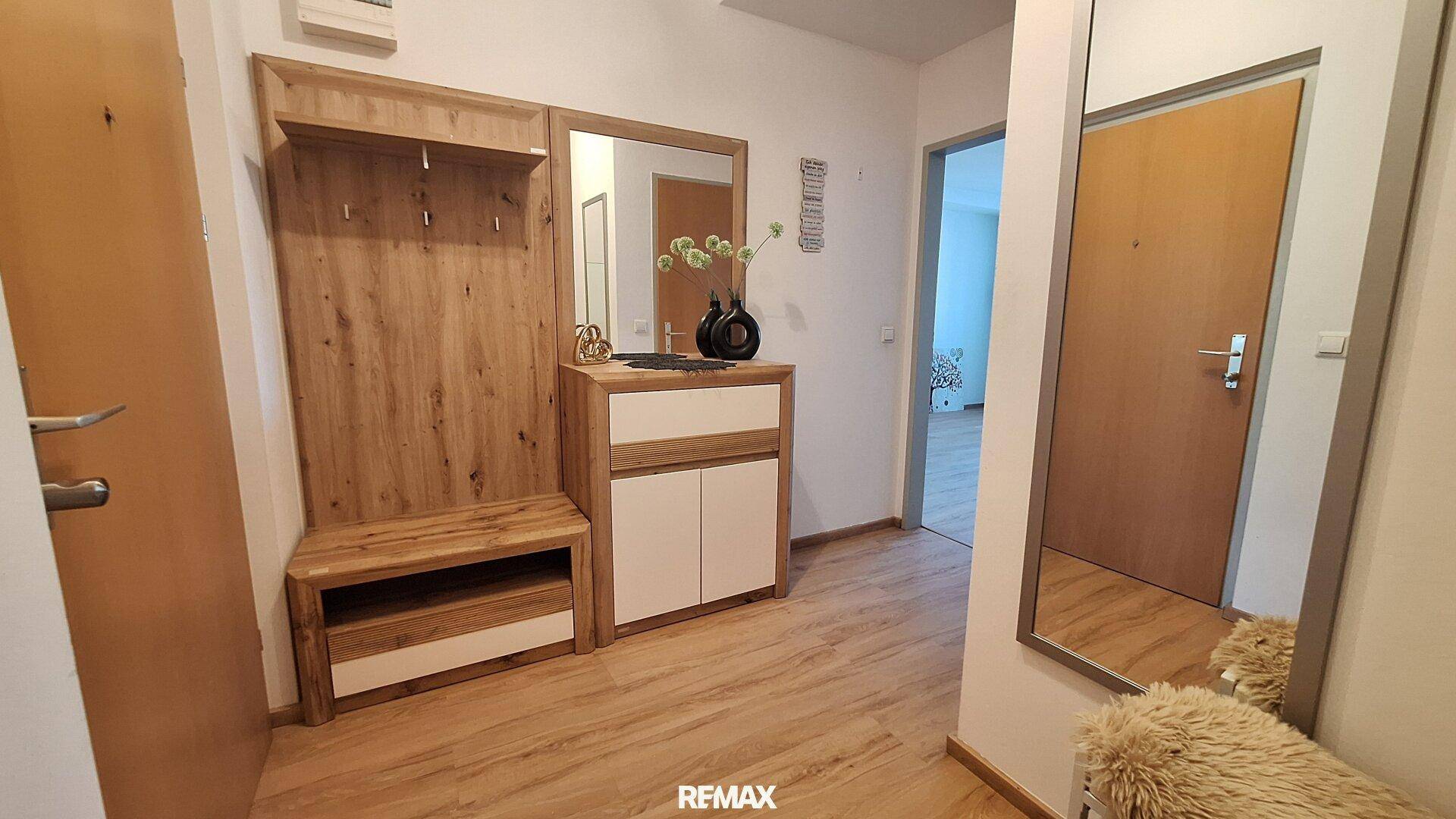Heller Eingangsbereich mit Garderobe, Spiegel und Laminatboden.