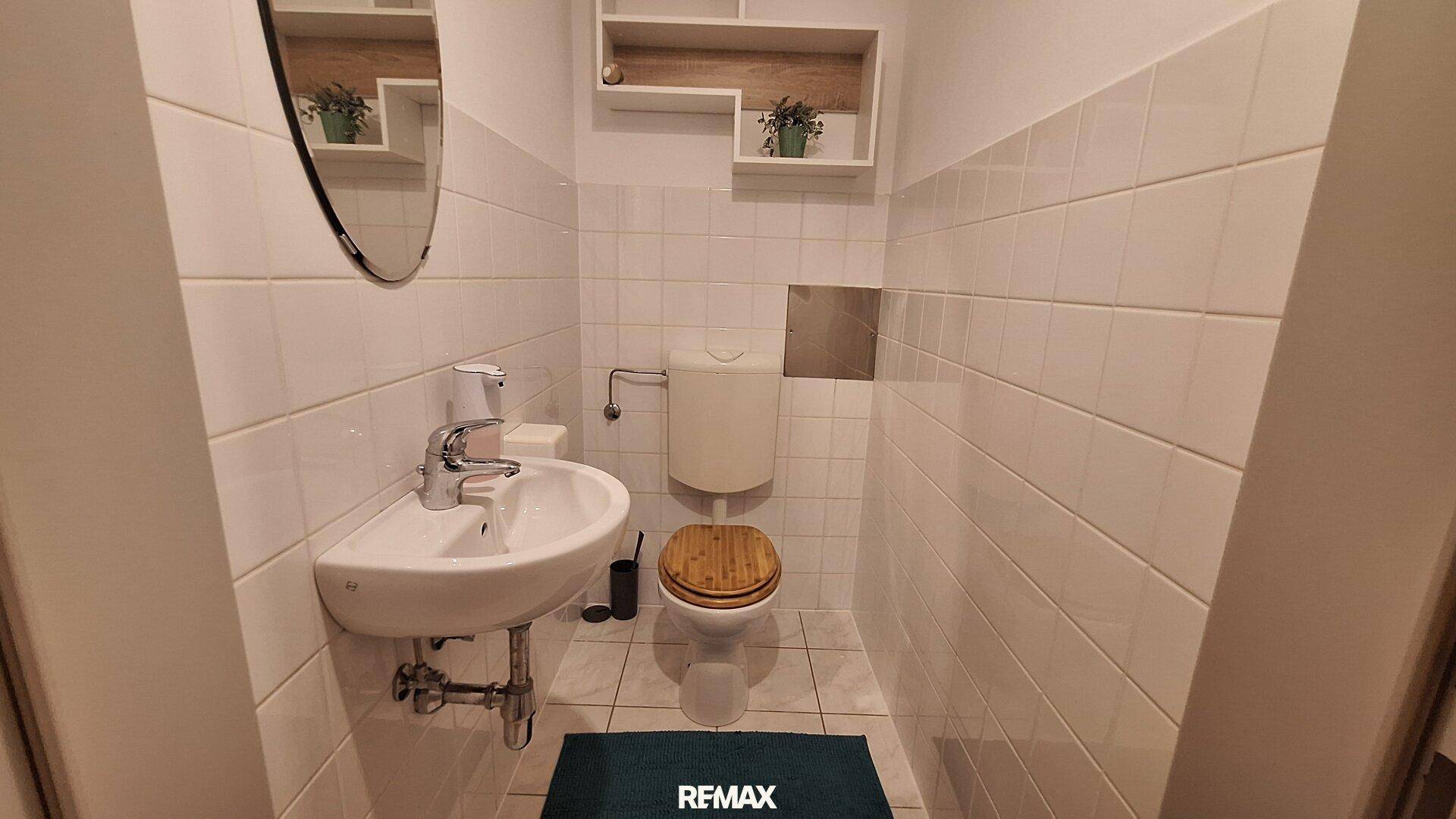 Kleines Gäste-WC mit Waschbecken, Toilette und weißen Fliesen.