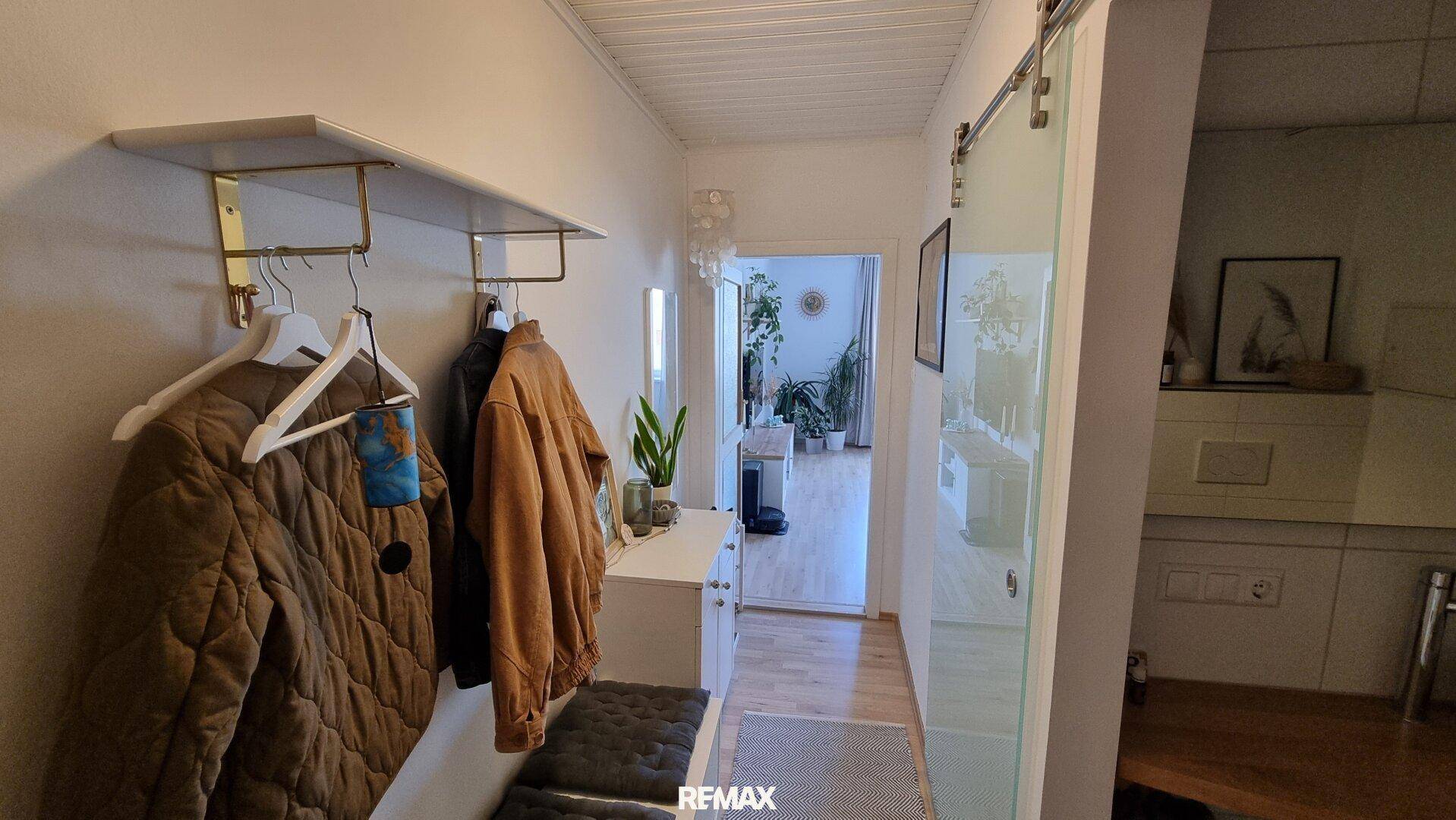 Heller Eingangsbereich mit Garderobe, Sitzbank und Blick in den angrenzenden Wohnbereich.