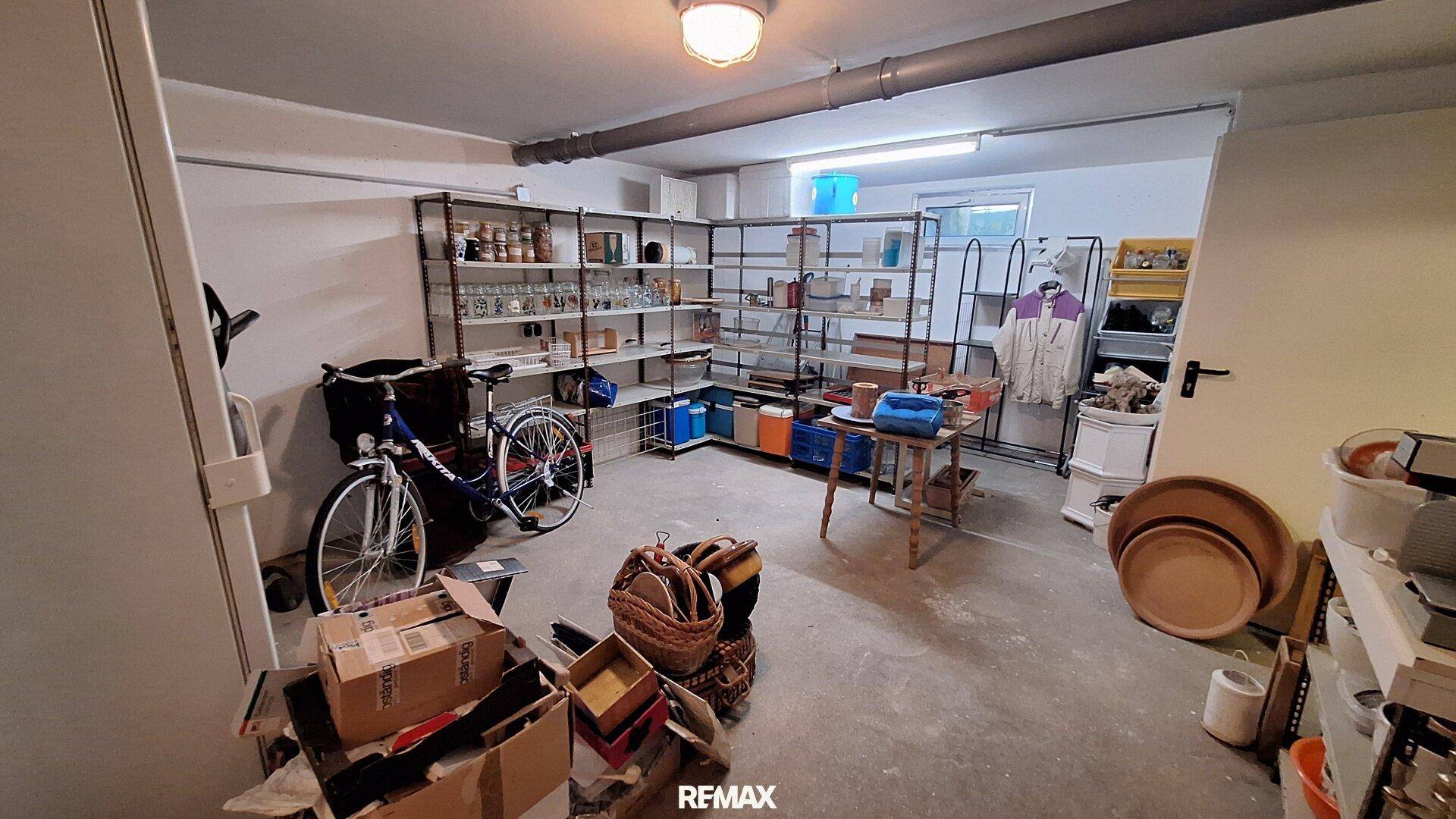 Geräumiger Kellerraum mit Regalen, Fahrrad und verschiedenen Lagergegenständen.