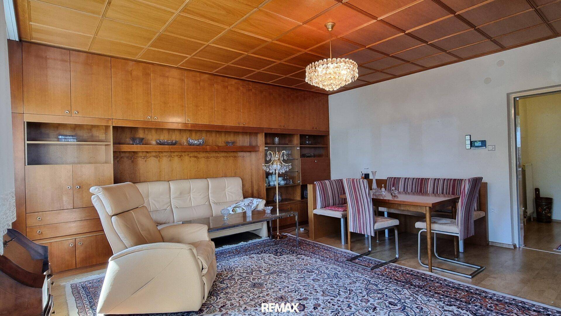 Gemütliches Wohnzimmer mit Holzvertäfelung, Teppichboden und traditionellen Einbaumöbeln.