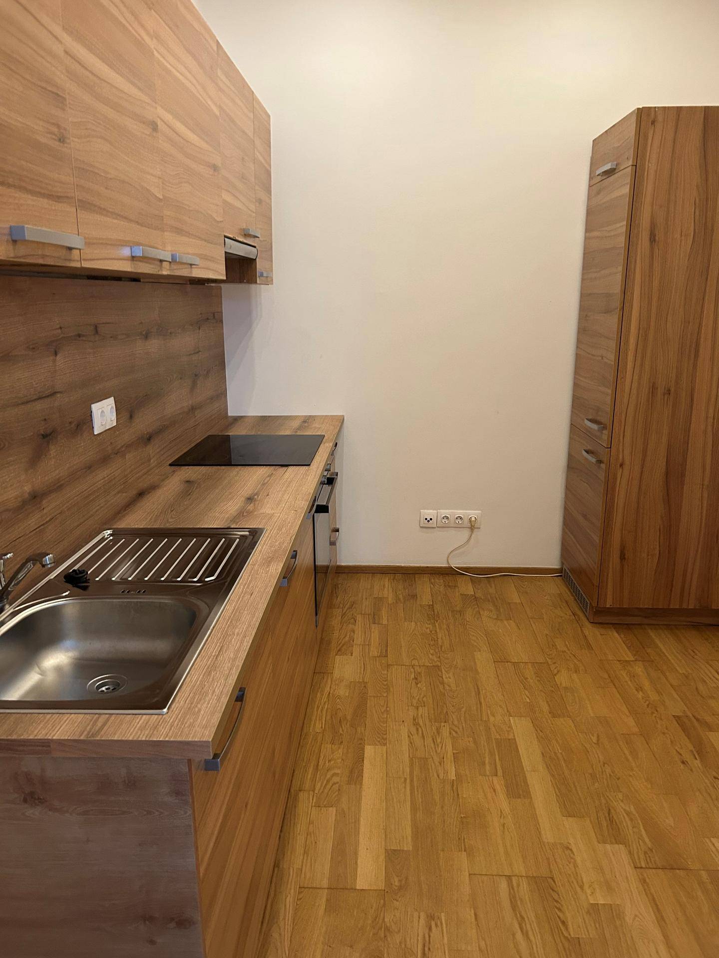 Funktionale Küchenzeile mit Holzoptik-Fronten, Spüle und Kochfeld, bereit zur Nutzung.