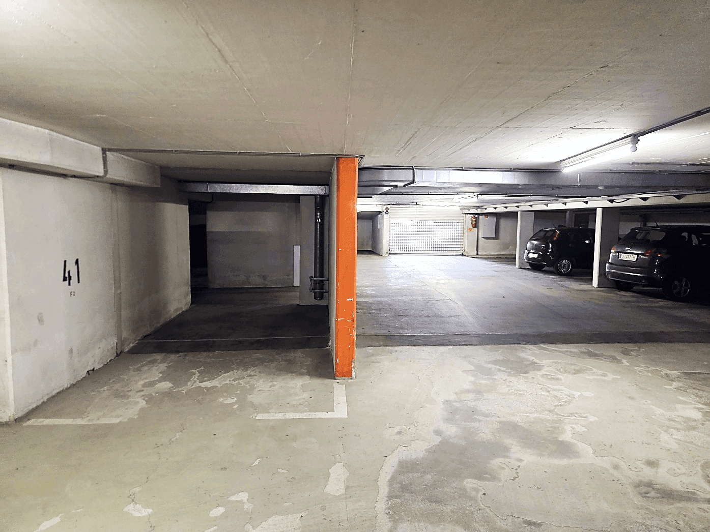 Tiefgarage mit Betonwänden und -decke, bietet Stellplätze für Fahrzeuge.