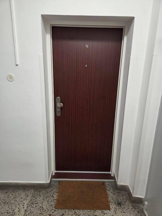 Eingangstür einer Wohnung in einem Mehrfamilienhaus mit einfacher Ausstattung.