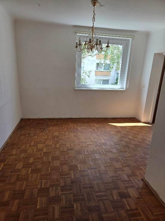 Geräumiges Zimmer mit Parkettboden, Kronleuchter und einem Fenster mit Blick auf die Umgebung.