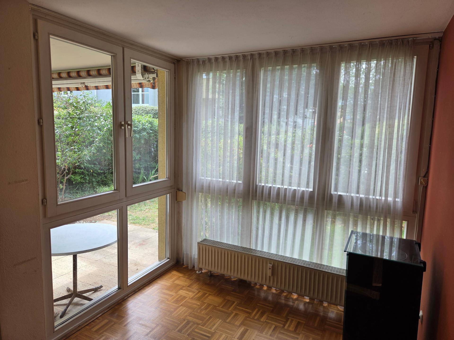 Heller Wohnbereich mit Parkettboden, großen Fenstern und Blick auf die Terrasse.