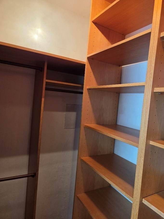 Praktische Holzregale und Kleiderstangen bieten viel Stauraum in diesem begehbaren Schrank.