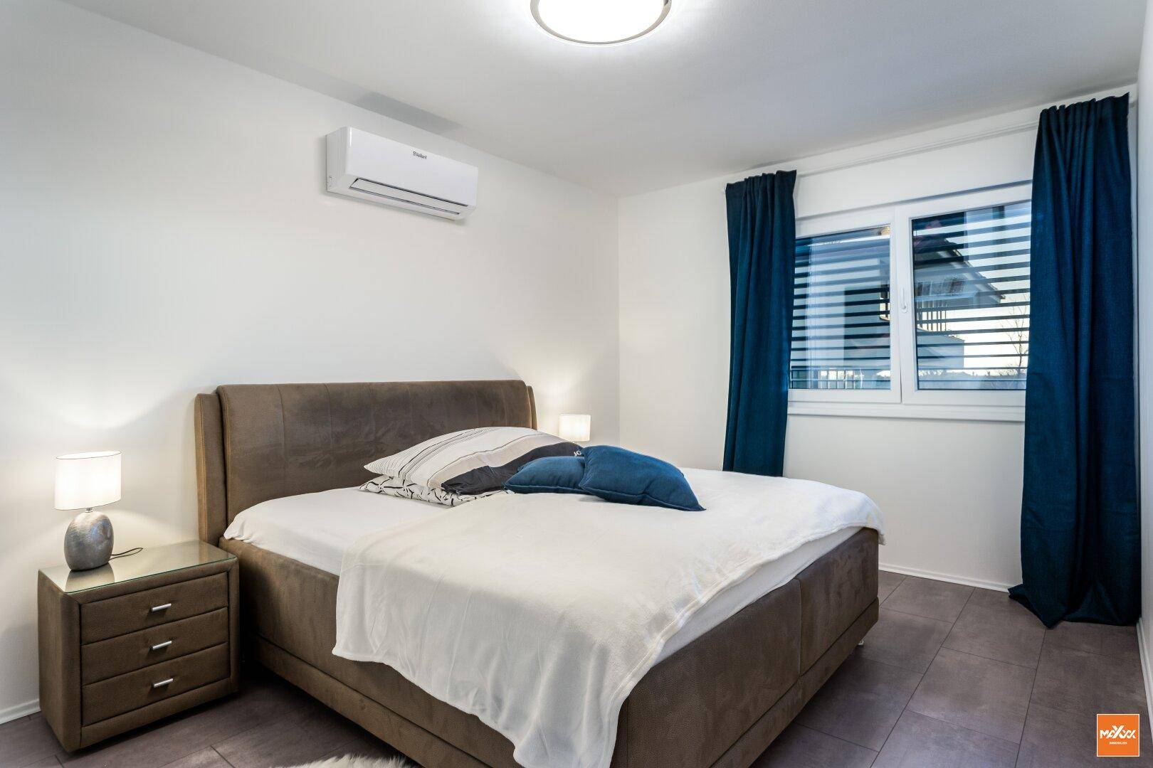 Gemütliches Schlafzimmer mit Doppelbett, Nachttischen und Klimaanlage.