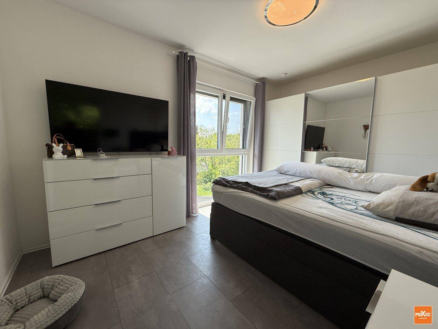 Helles Schlafzimmer mit Doppelbett, Kleiderschrank und großem Fenster mit Ausblick.