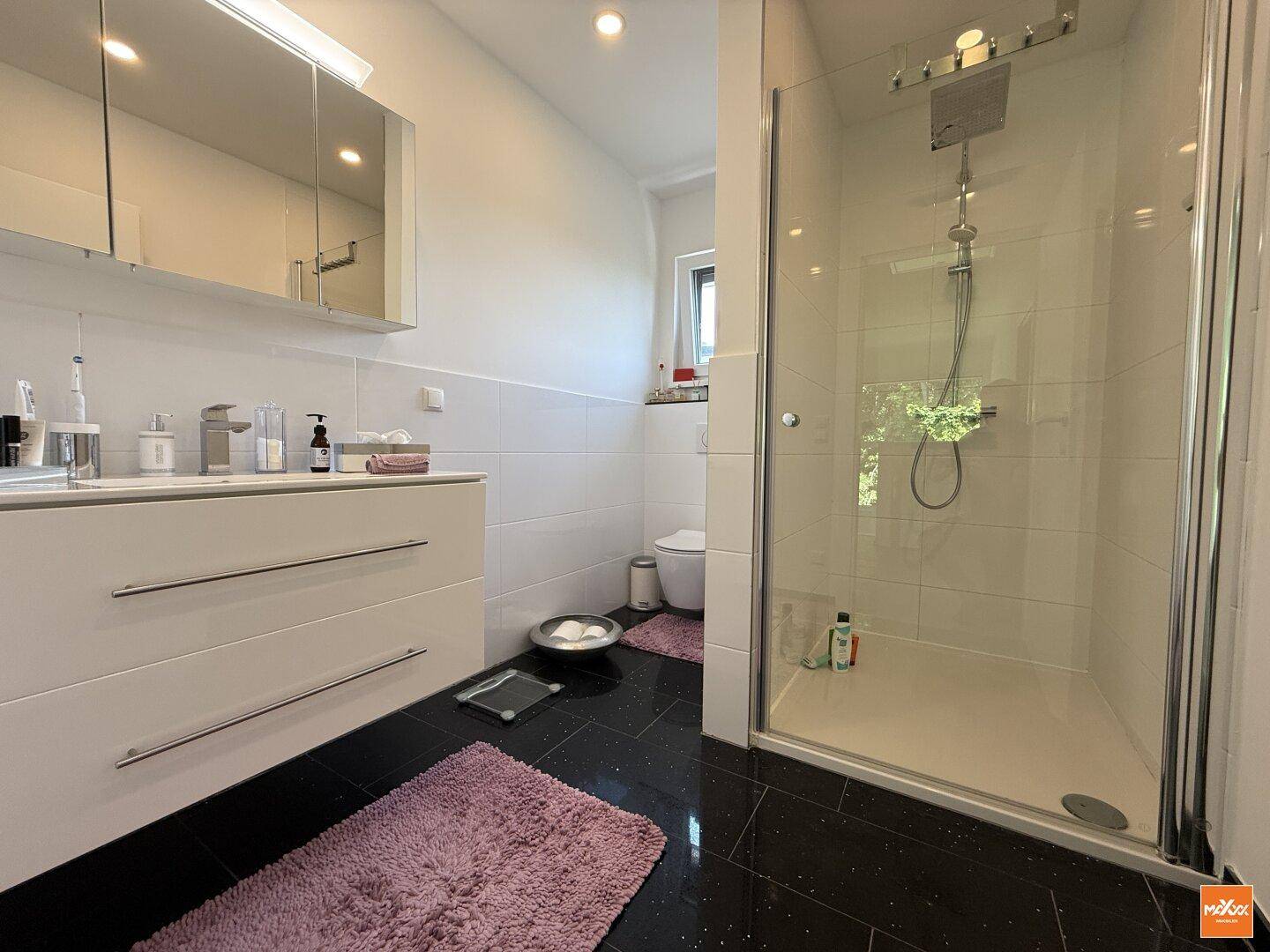 Modernes Badezimmer mit großer Dusche, Doppelwaschtisch und Spiegelschrank.