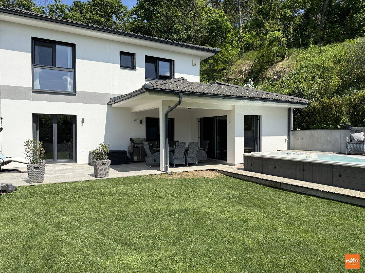 Gepflegter Garten mit Rasenfläche, überdachter Terrasse und Zugang zum Haus.
