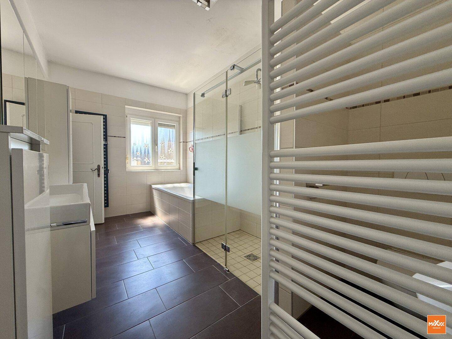 Modernes Badezimmer mit begehbarer Dusche, Badewanne, Doppelwaschbecken und Handtuchheizkörper.
