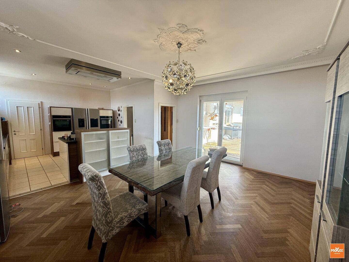 Eleganter Essbereich mit Kronleuchter, Parkettboden und direktem Zugang zu einer Außenterrasse.