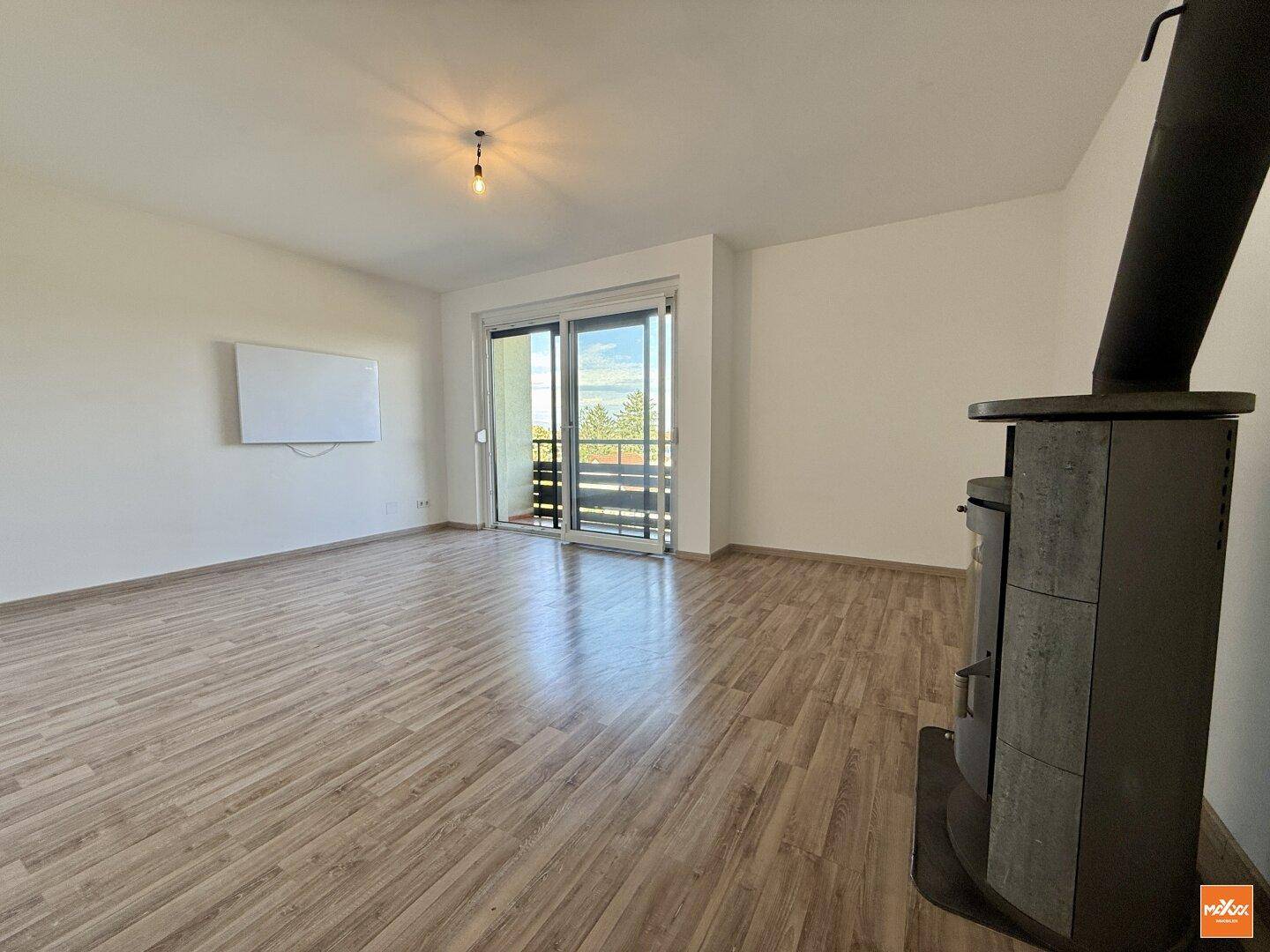 Geräumiges Wohnzimmer mit gemütlichem Holzofen und Zugang zu einem Balkon.