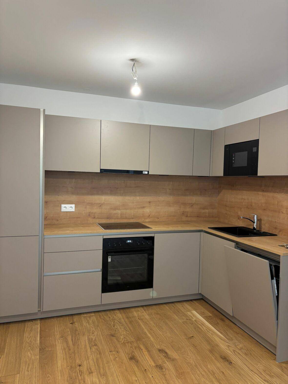 Moderne Einbauküche in Beige mit Holzoptik-Arbeitsplatte und integrierten Geräten.