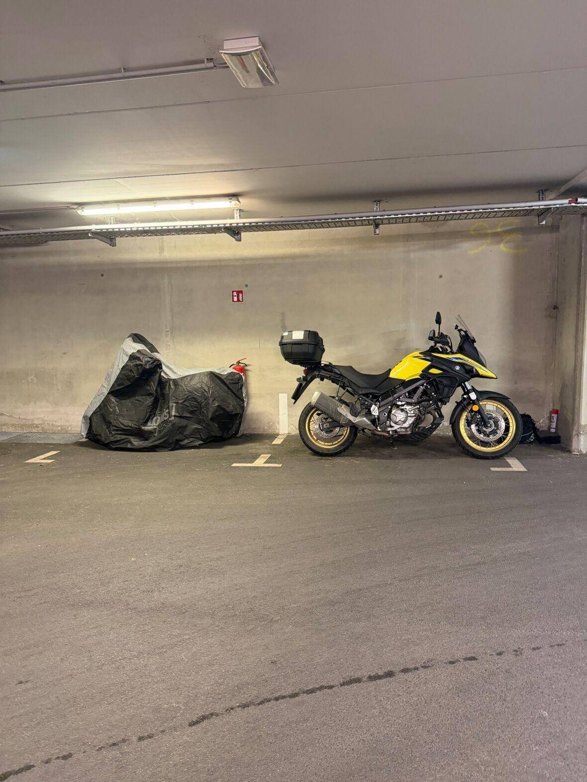 Tiefgaragenstellplatz mit zwei Motorrädern und sauberem Betonboden.