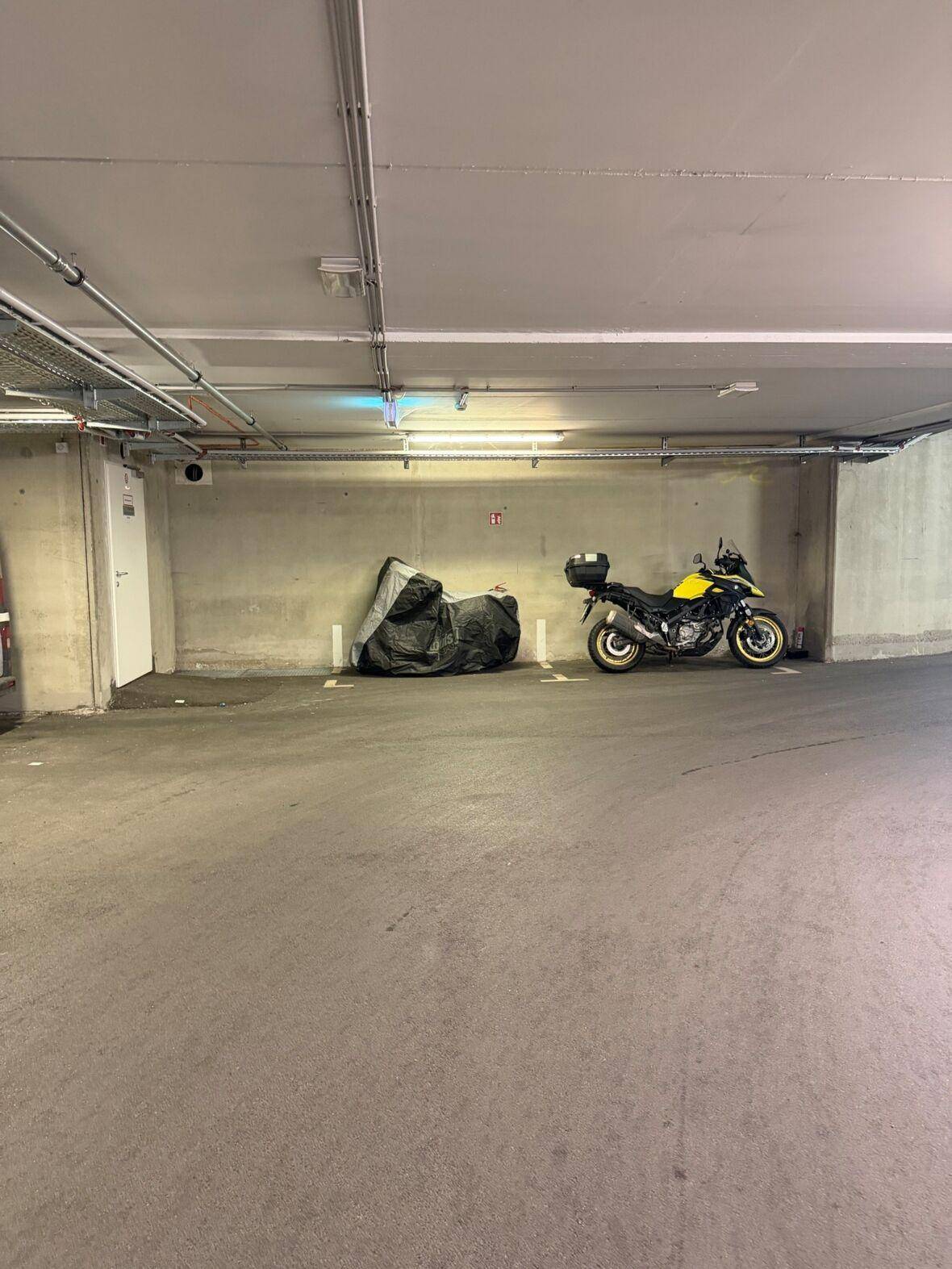 Geräumiger Tiefgaragenstellplatz mit Motorrädern und Betonwänden.