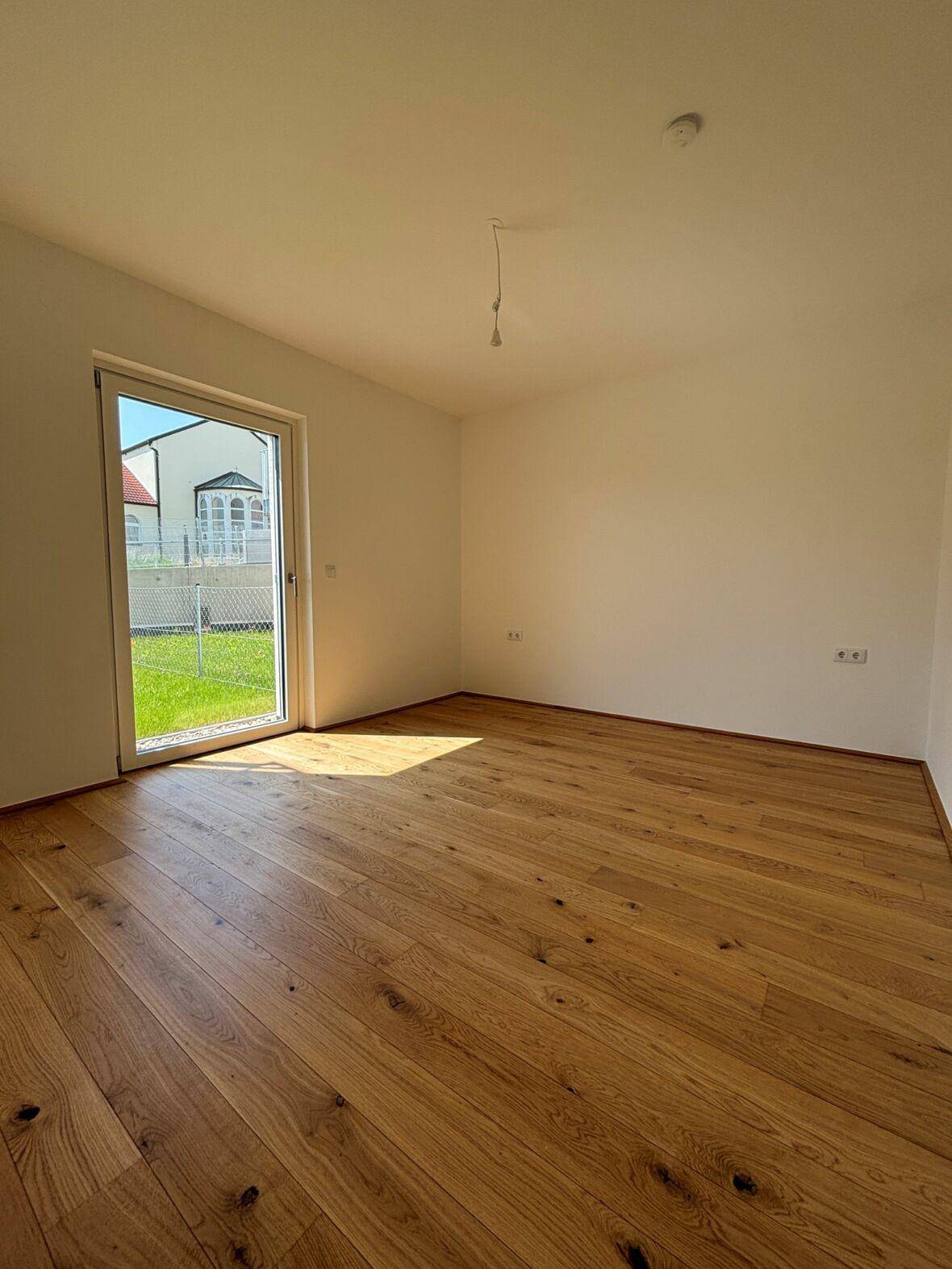 Sonniger Raum mit hellem Holzboden und direktem Zugang zum Gartenbereich.