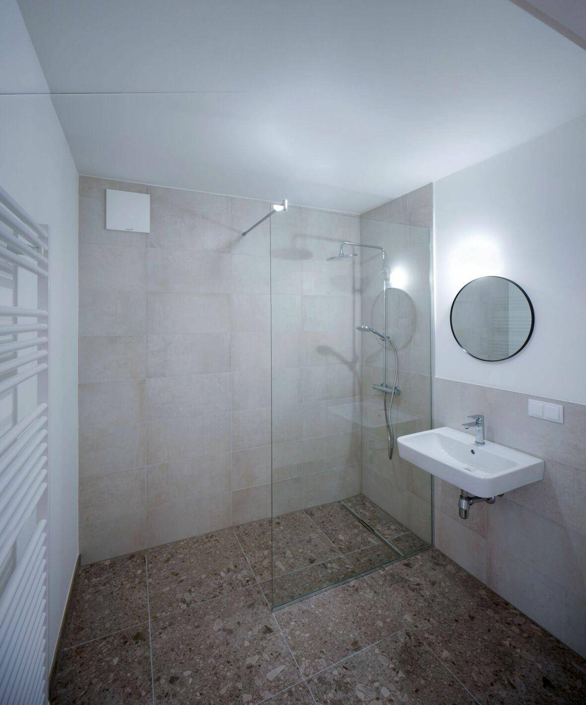 Modernes Badezimmer mit ebenerdiger Dusche, Einzelwaschbecken und beheiztem Handtuchhalter.