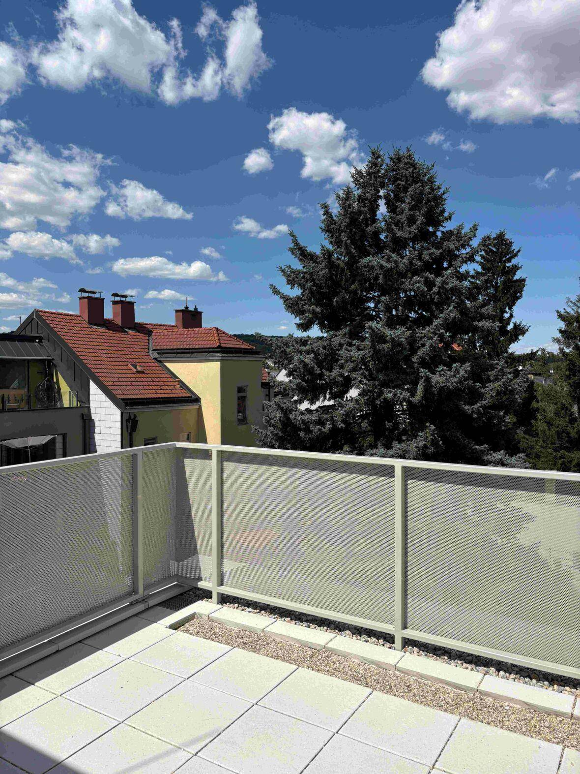 Geräumige Terrasse mit Fliesenboden und weitem Blick über die Dächer und Bäume.