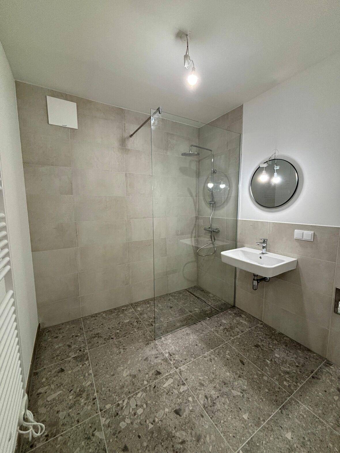 Modernes Badezimmer mit begehbarer Dusche, großformatigen Fliesen, Einzelwaschbecken und Handtuchheizkörper.
