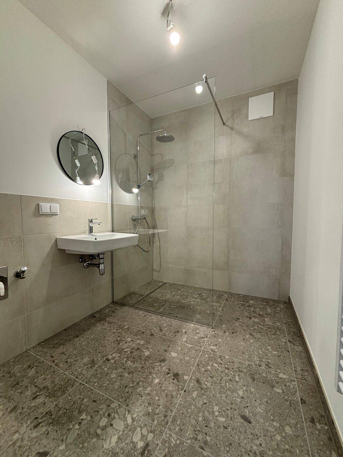 Modernes Badezimmer mit ebenerdiger Dusche, Einzelwaschbecken und Fliesenboden, inklusive Handtuchheizkörper.