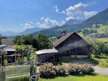 Idyllisches Holzhaus mit Satteldach und Garten in ländlicher Umgebung mit Bergblick.