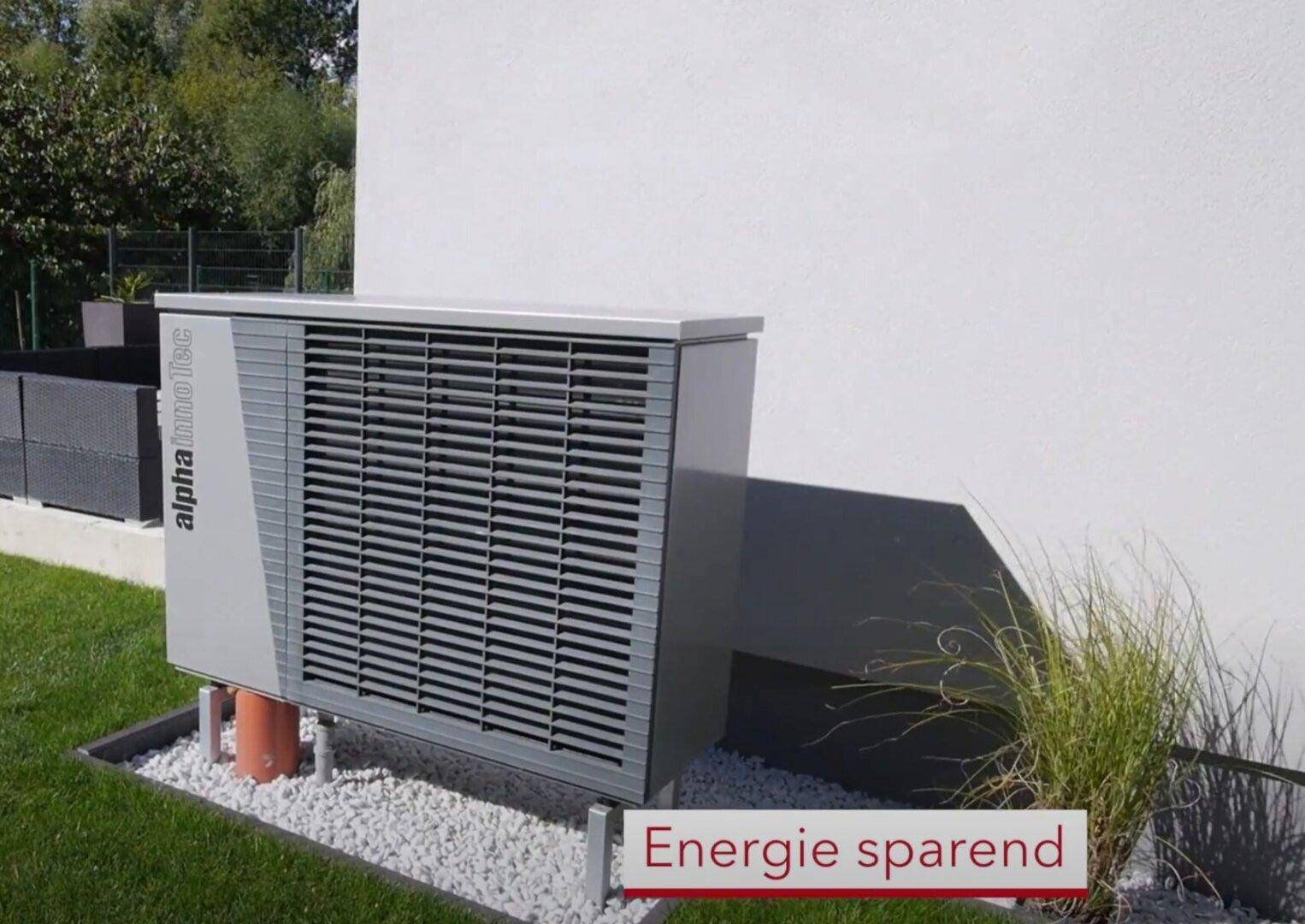 Moderne Wärmepumpe an der Hauswand, umgeben von Kies und Rasen, für effiziente Heizung.