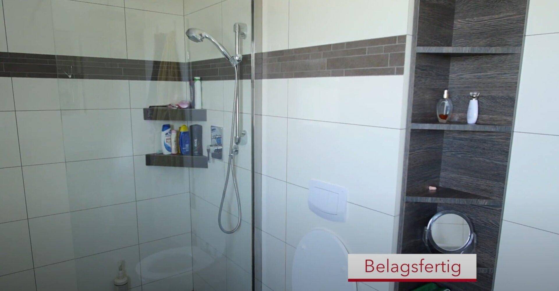 Modernes Badezimmer mit begehbarer Dusche, Wand-WC und stilvollen Fliesen in Grau und Weiß.