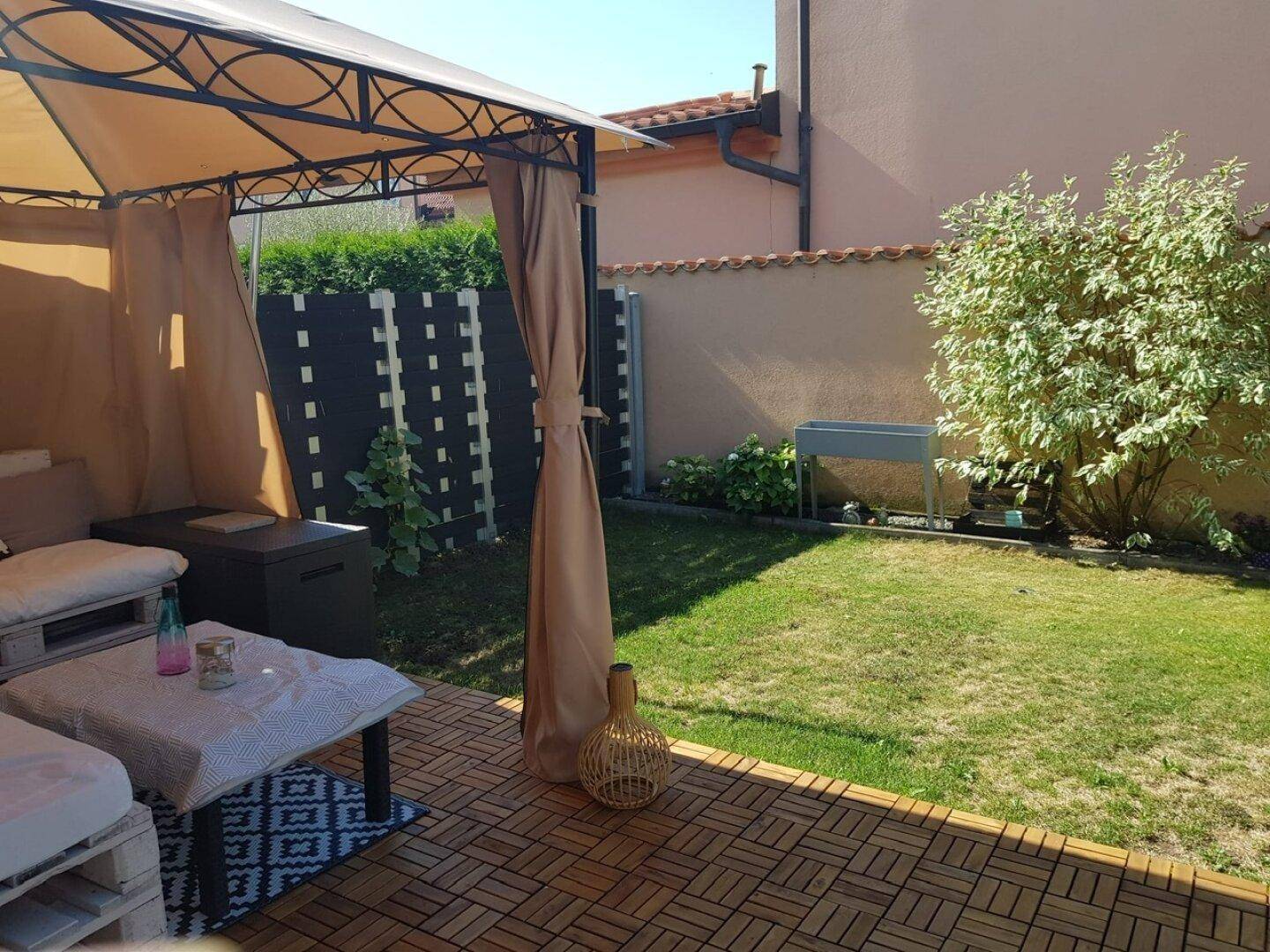 Gepflegter Garten mit Rasenfläche, überdachtem Sitzbereich und Holzterrasse für Outdoor-Aktivitäten.