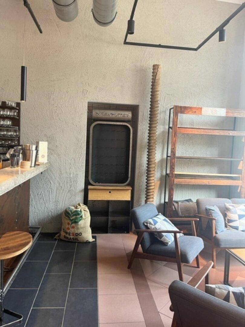 Barboden mit Fliesen, Sitzgelegenheiten und einem Sack Kaffeebohnen, der eine gemütliche Atmosphäre schafft.