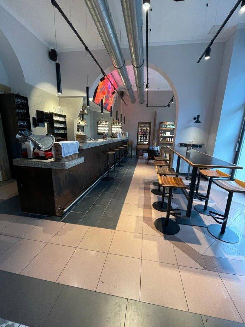 Langer Barbereich mit Hockern und einem Mix aus hellen und dunklen Fliesenböden in einem modernen Ambiente.