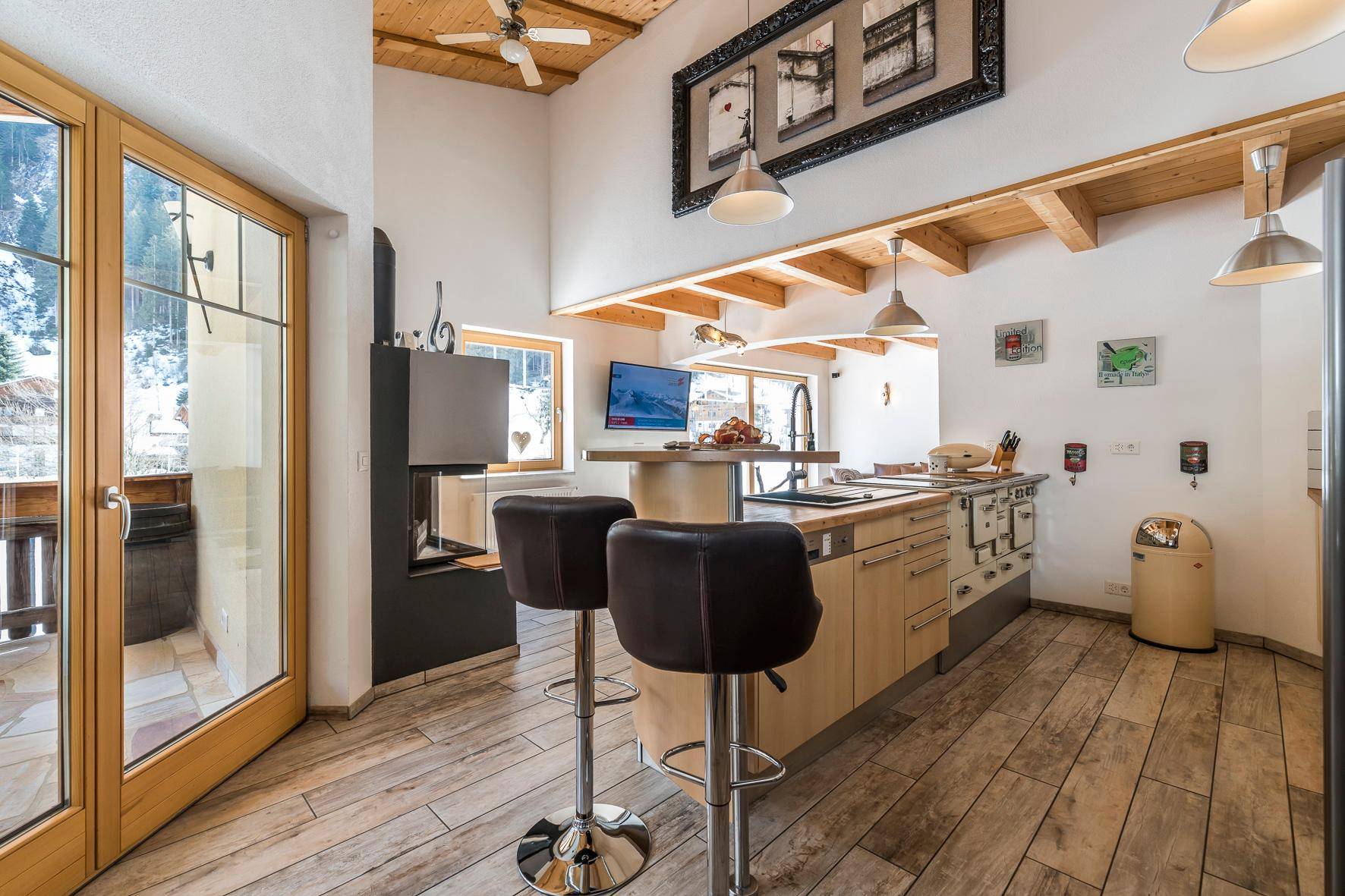 Moderne Küche mit Kochinsel, Barhockern und offenem Übergang zum Wohnbereich mit Kamin.