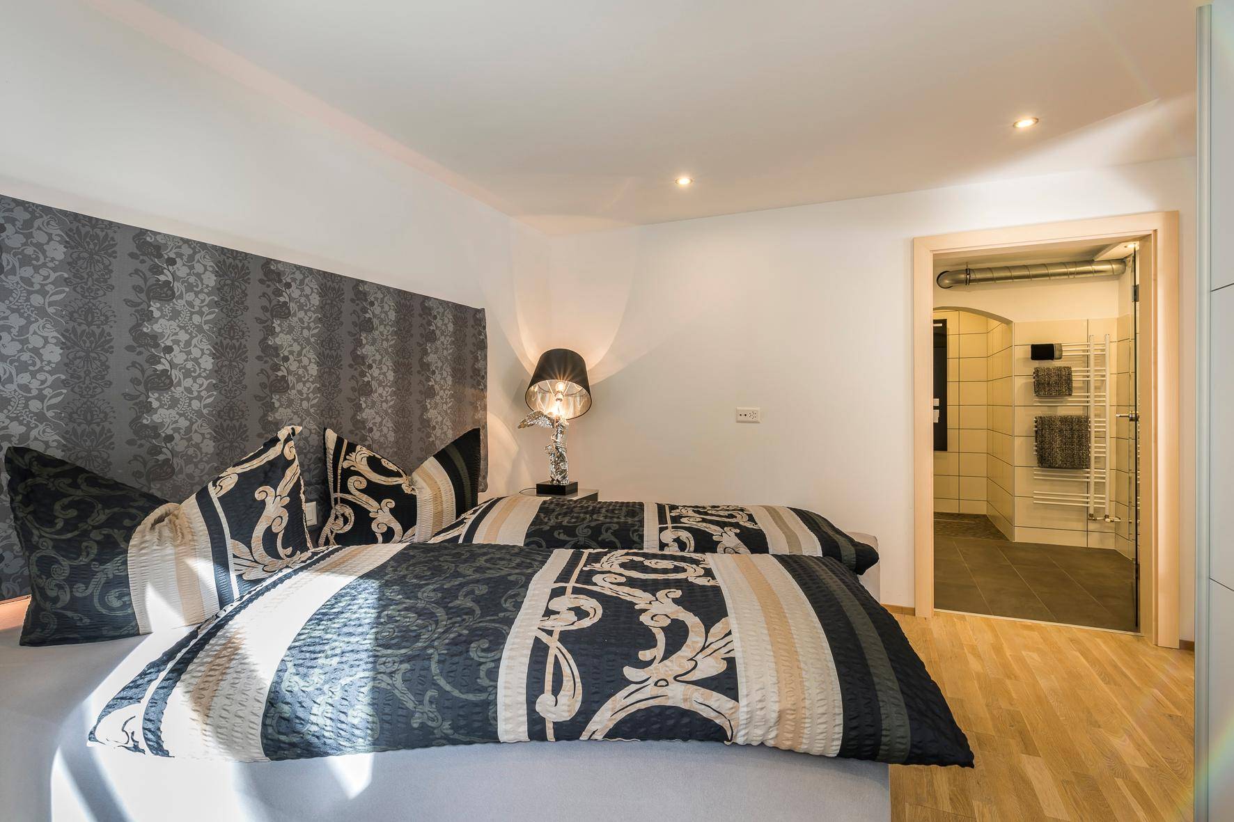 Modernes Schlafzimmer mit gemusterter Tapete und direktem Zugang zu einem stilvollen Badezimmer.