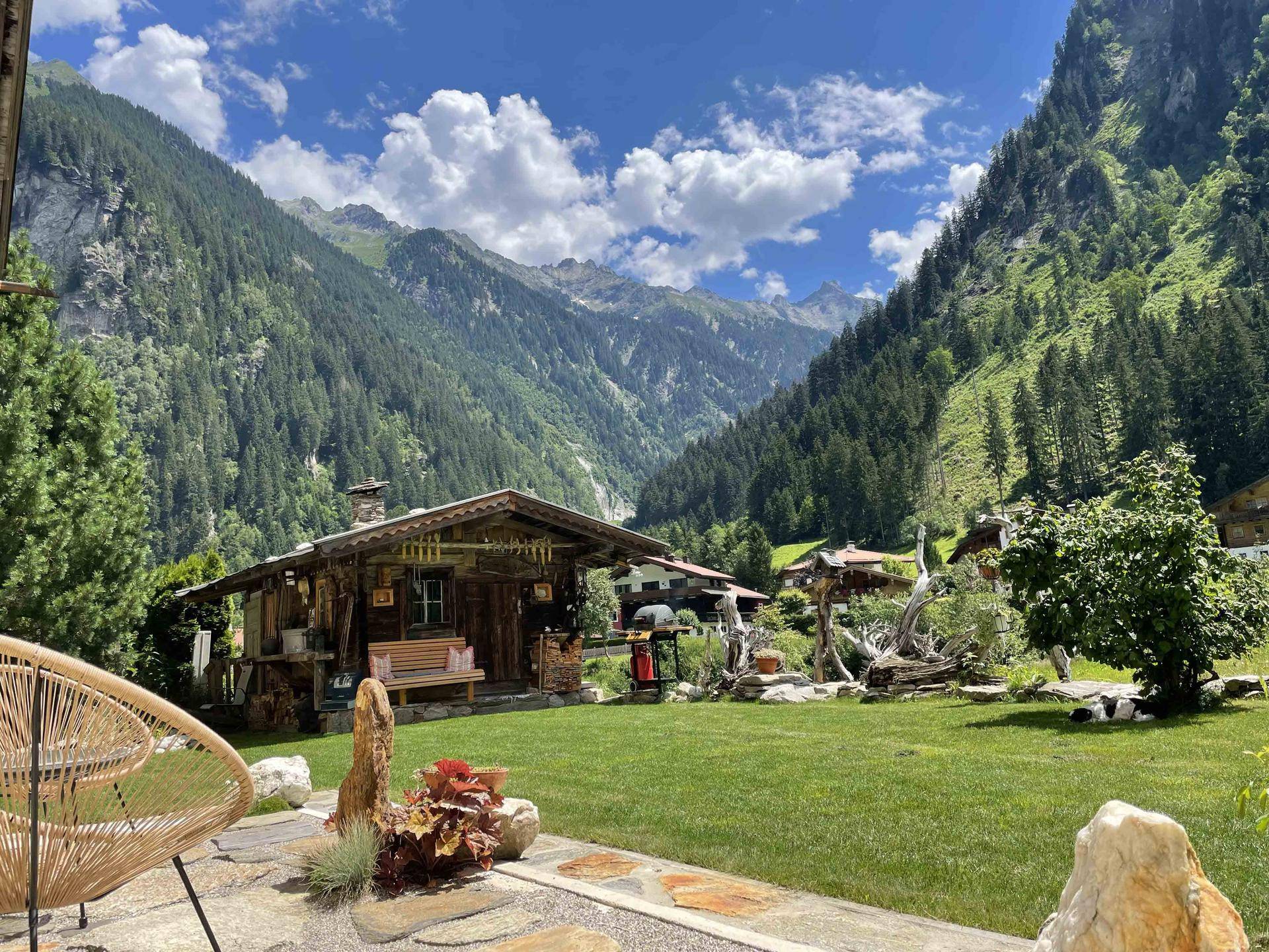 Gepflegter Garten mit Rasenfläche, Sitzgelegenheiten und atemberaubendem Blick auf die umliegenden Berge.