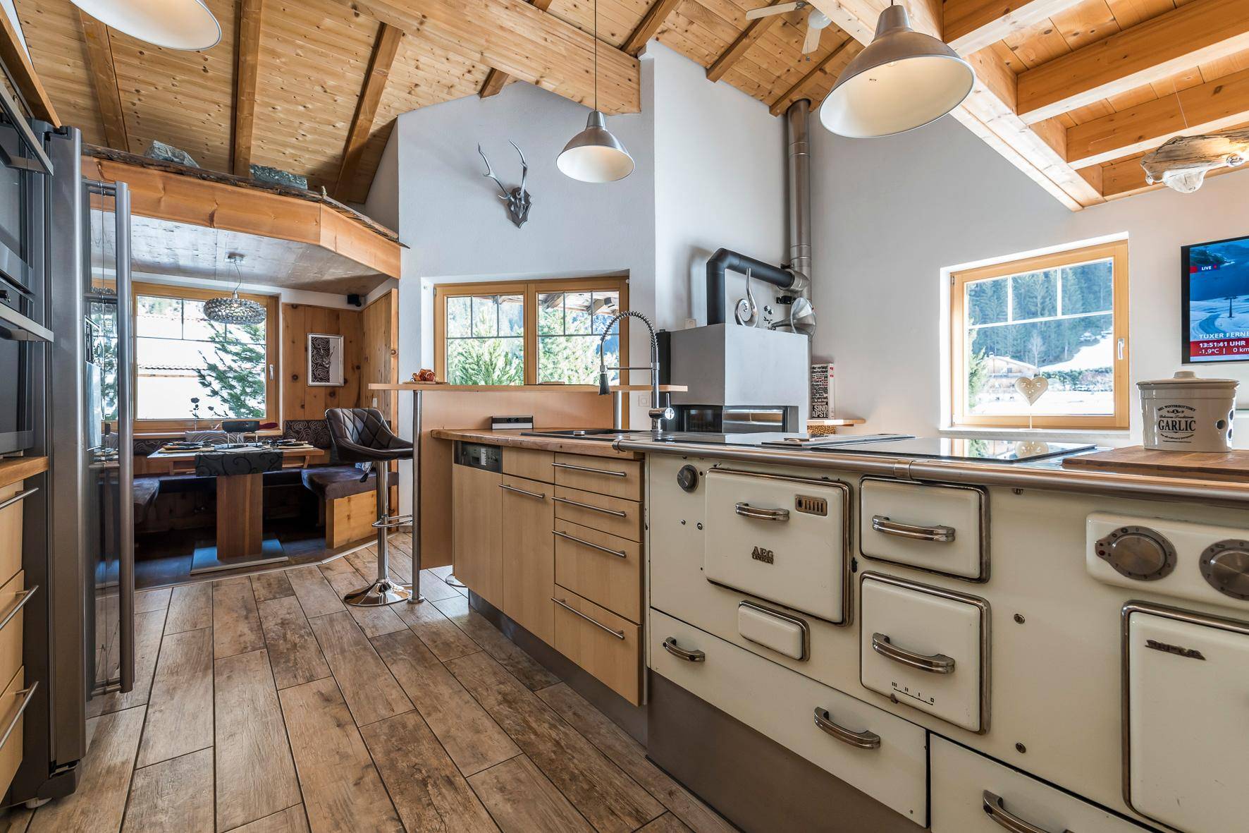 Rustikale Küche mit traditionellem Holzherd, Holzbalkendecke und Essbereich mit Bergblick.