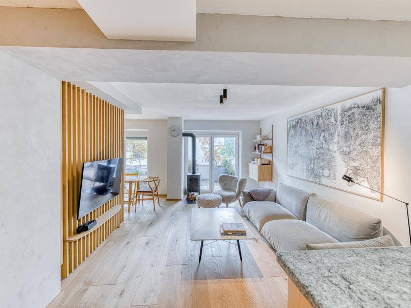 Offener Wohn- und Essbereich mit Holzboden, Kaminofen und moderner Einrichtung.