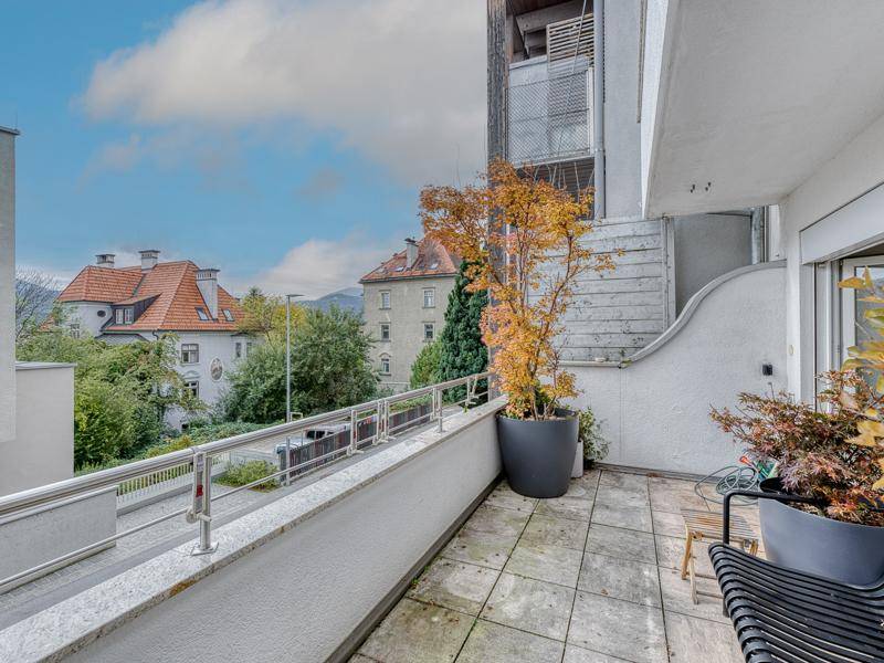 Geräumiger Balkon mit Fliesenboden, Pflanzen und Blick auf die Nachbarschaft.
