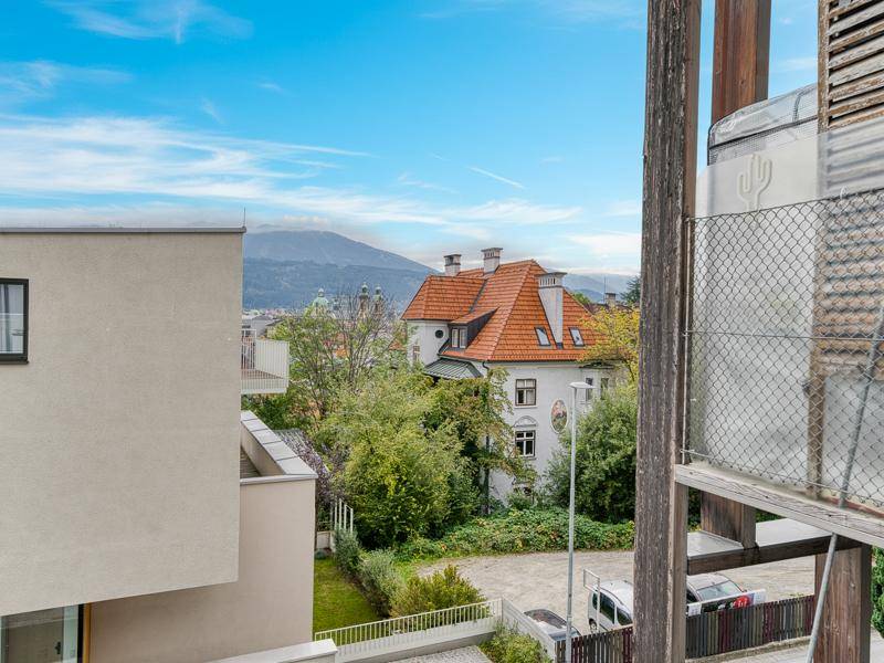 Panoramablick auf die Stadt und die umliegenden Berge von einem Balkon aus.