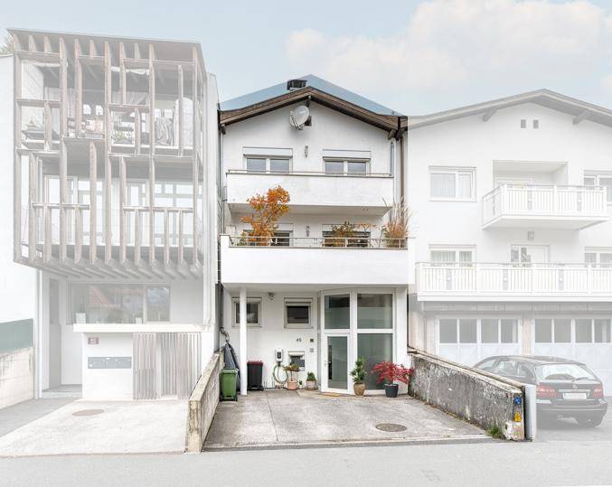 Weißes Mehrfamilienhaus mit Balkonen und moderner Architektur in urbaner Umgebung.