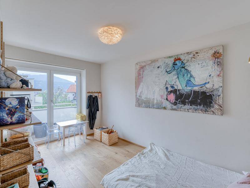 Schlafzimmer mit Holzboden, großem Fenster und Zugang zu einem Balkon.