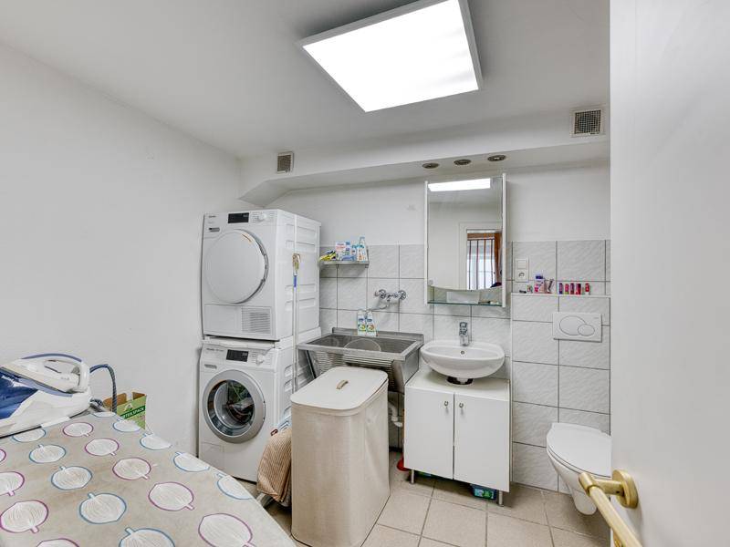 Praktischer Hauswirtschaftsraum mit Waschmaschine, Trockner, Spülbecken und WC.